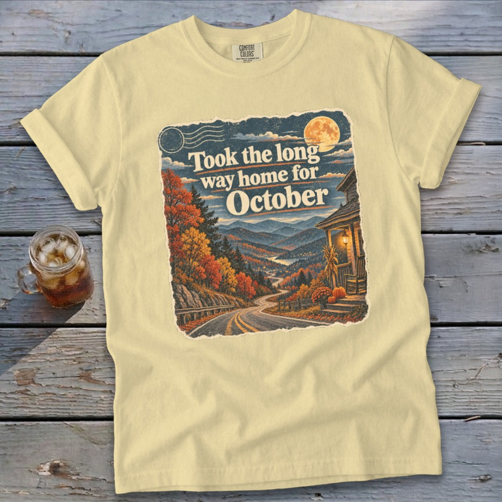 Yellow t-shirt graphic with text "Took the long way home for October" and autumn mountain scene.
