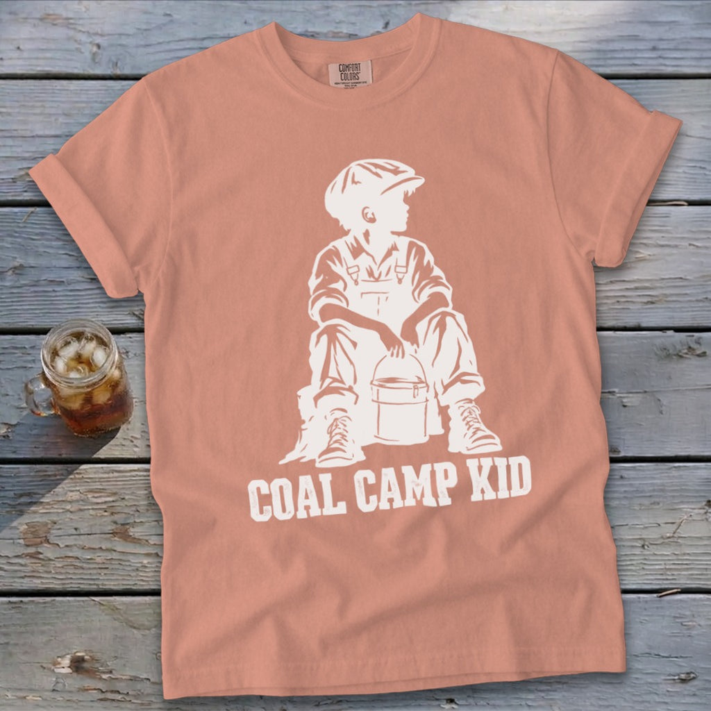 Peach t-shirt with white graphic of boy in overalls and hat holding bucket, text "Coal Camp Kid."
