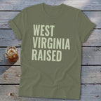 Olive green t-shirt with "WEST VIRGINIA RAISED" text in light green.