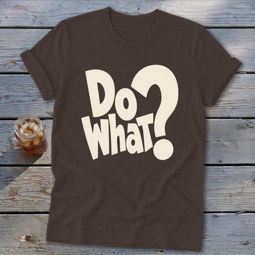 A dark brown crewneck t-shirt with rolled-up sleeves, featuring the white text "Do what?" on the chest, laid flat on a rustic wooden surface next to a glass of iced tea.