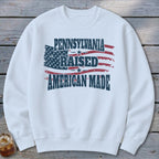 A white crewneck sweatshirt featuring a distressed American flag and the text Pennsylvania Raised American Made.