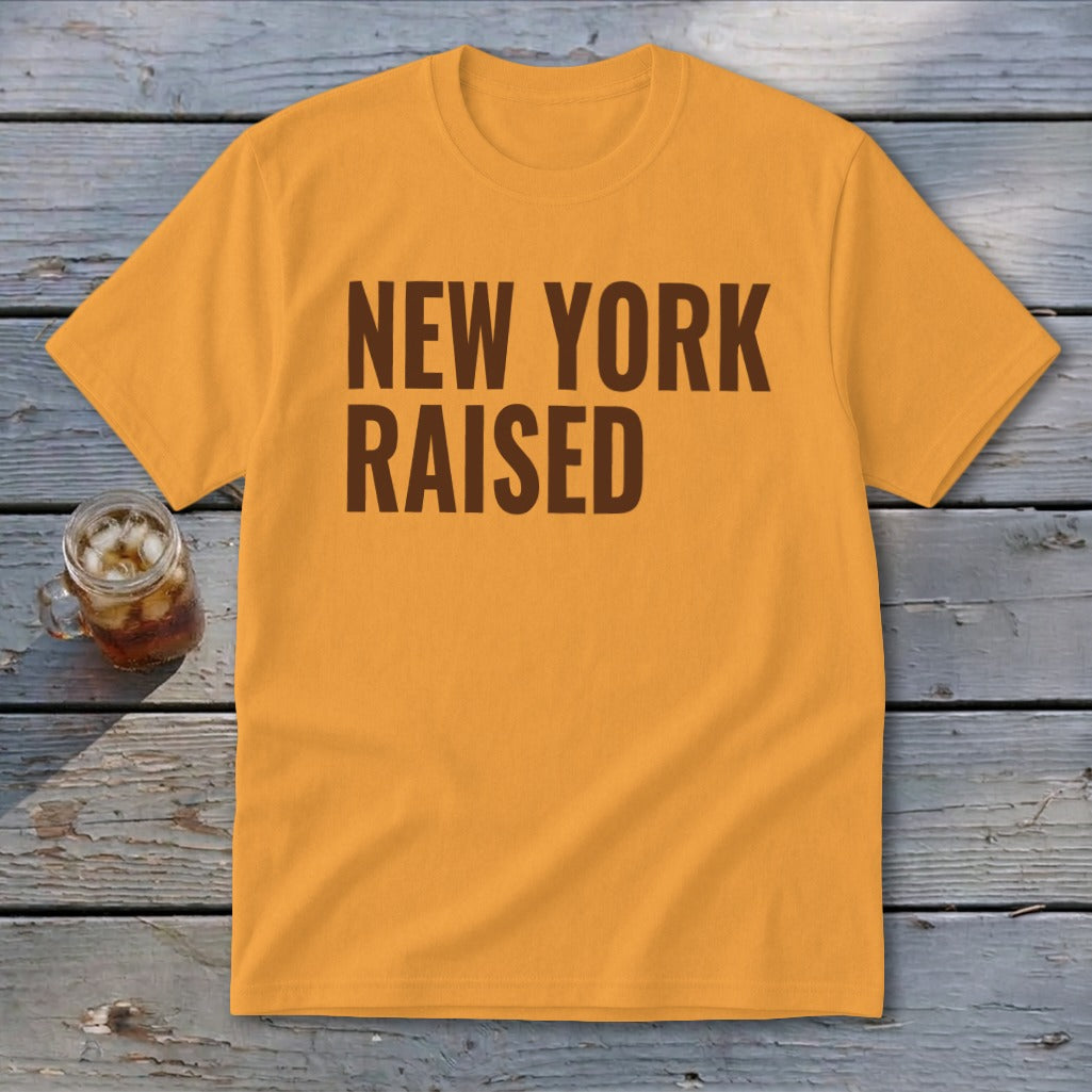 Orange t-shirt with brown text "NEW YORK RAISED" and a glass of iced drink.