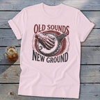 Light pink t-shirt featuring a red banjo graphic and the text OLD SOUNDS NEW GROUND.