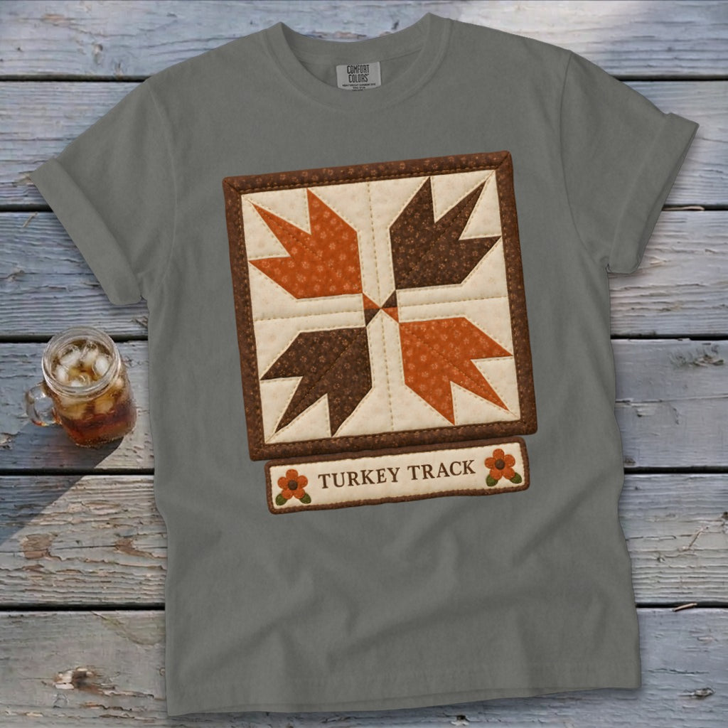 Grey t-shirt with a "Turkey Track" quilt block design and small floral accents.