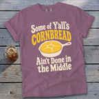 Mauve t-shirt printed with the text "Some of Y'all's Cornbread Ain't Done in the Middle" and a skillet graphic.
