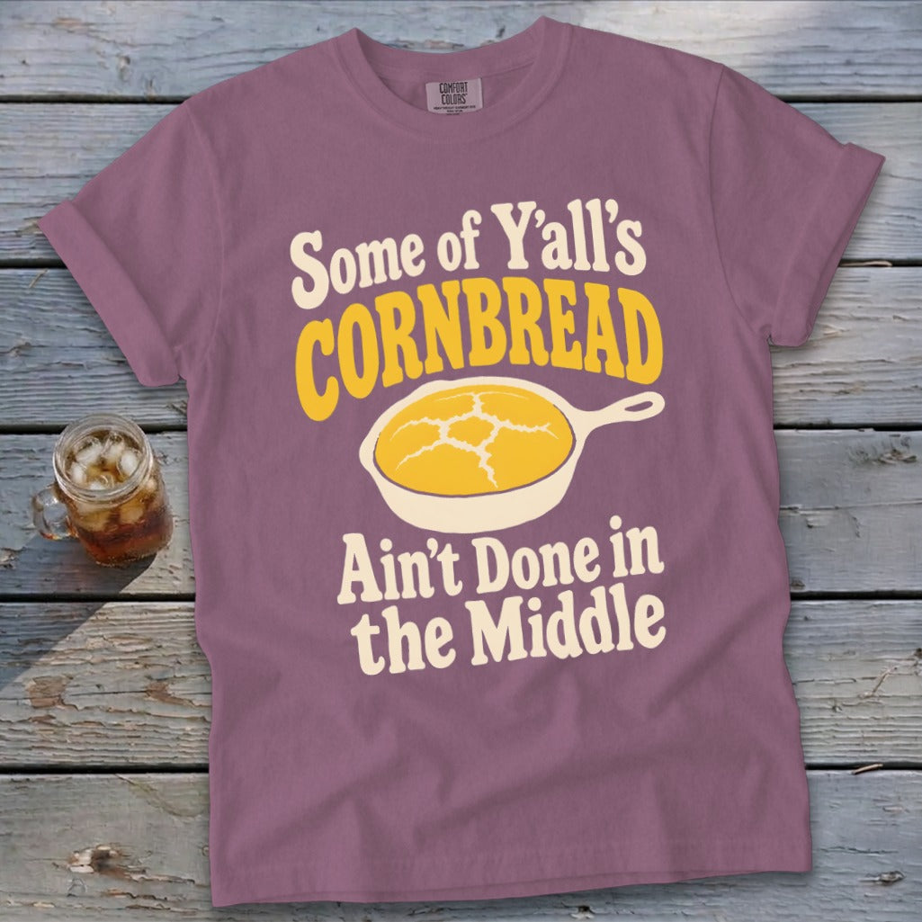 Mauve t-shirt printed with the text "Some of Y'all's Cornbread Ain't Done in the Middle" and a skillet graphic.