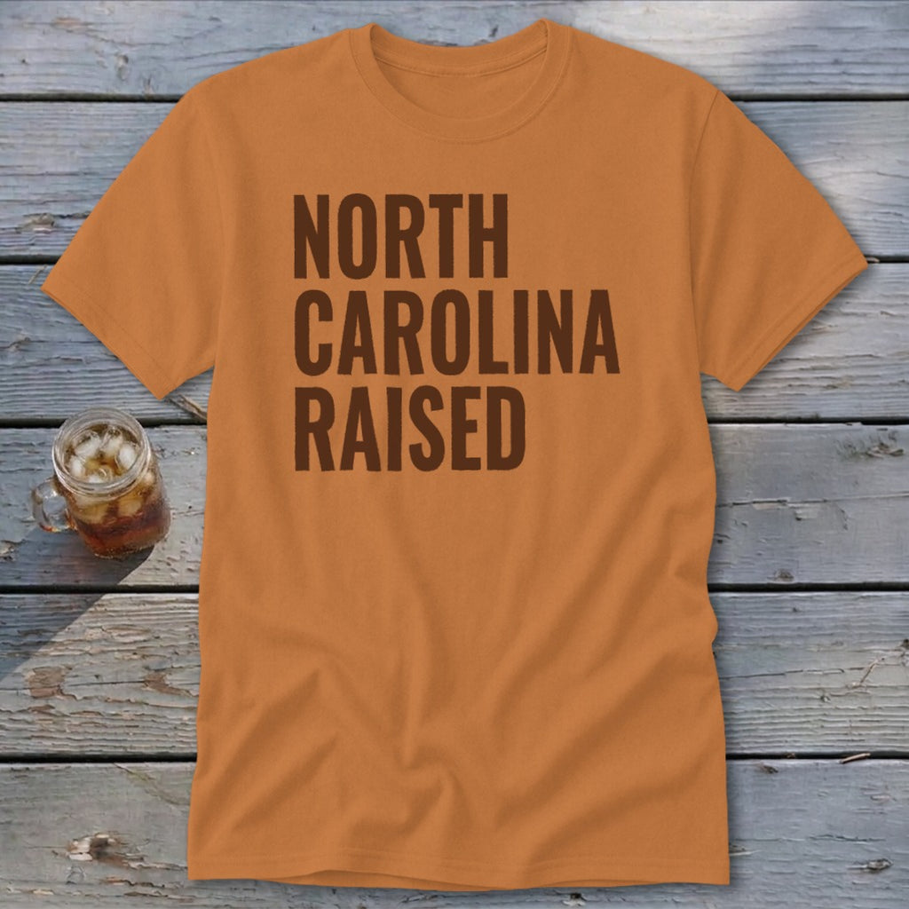 Orange t-shirt with "NORTH CAROLINA RAISED" text in brown block letters.