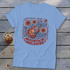 Light blue t-shirt featuring a folk-art graphic of a guitar, sunflowers, and the text MOUNTAIN MELODIES.