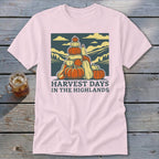 Light pink t-shirt featuring a retro graphic of stacked pumpkins, mountains, and the text Harvest Days in the Highlands.