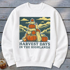White crewneck sweatshirt featuring a graphic of stacked pumpkins with landscape scenery and text reading Harvest Days in the Highlands.