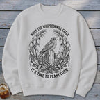 Off-white crewneck sweatshirt featuring a black graphic of a bird on a post surrounded by corn with text.