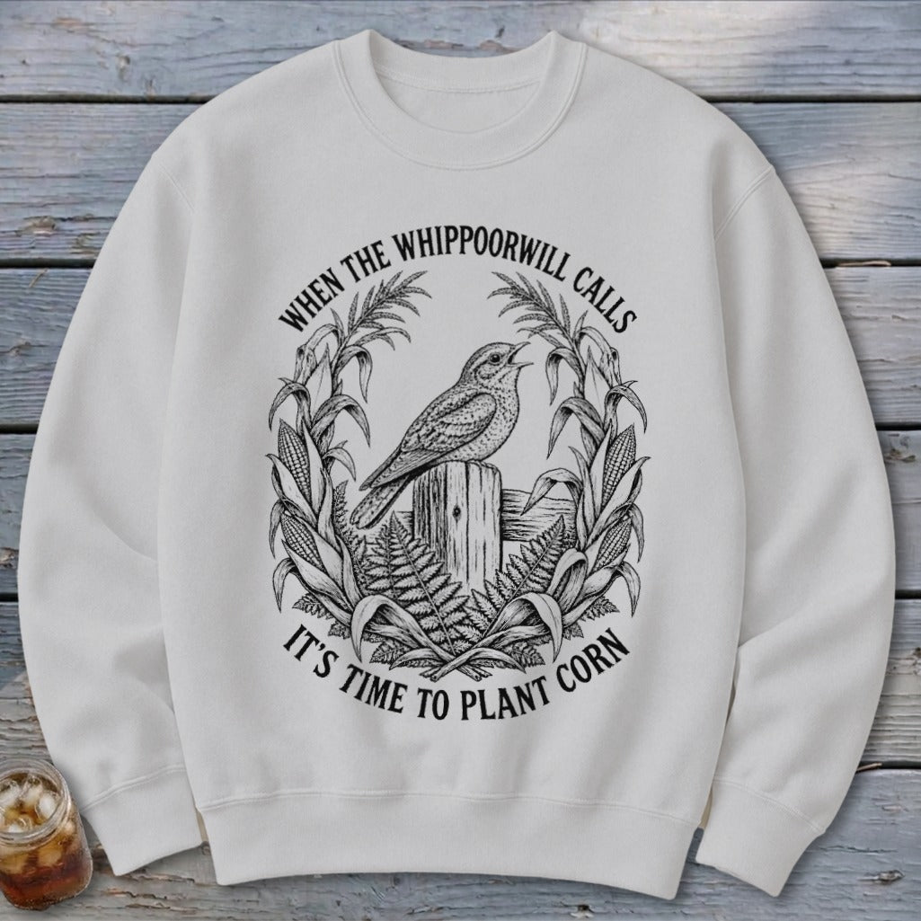 Off-white crewneck sweatshirt featuring a black graphic of a bird on a post surrounded by corn with text.