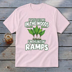 A light pink t-shirt featuring green text reading IF YOU SEE ME IN THE WOODS I'M HUNTIN' RAMPS above and below an illustration of wild ramps.