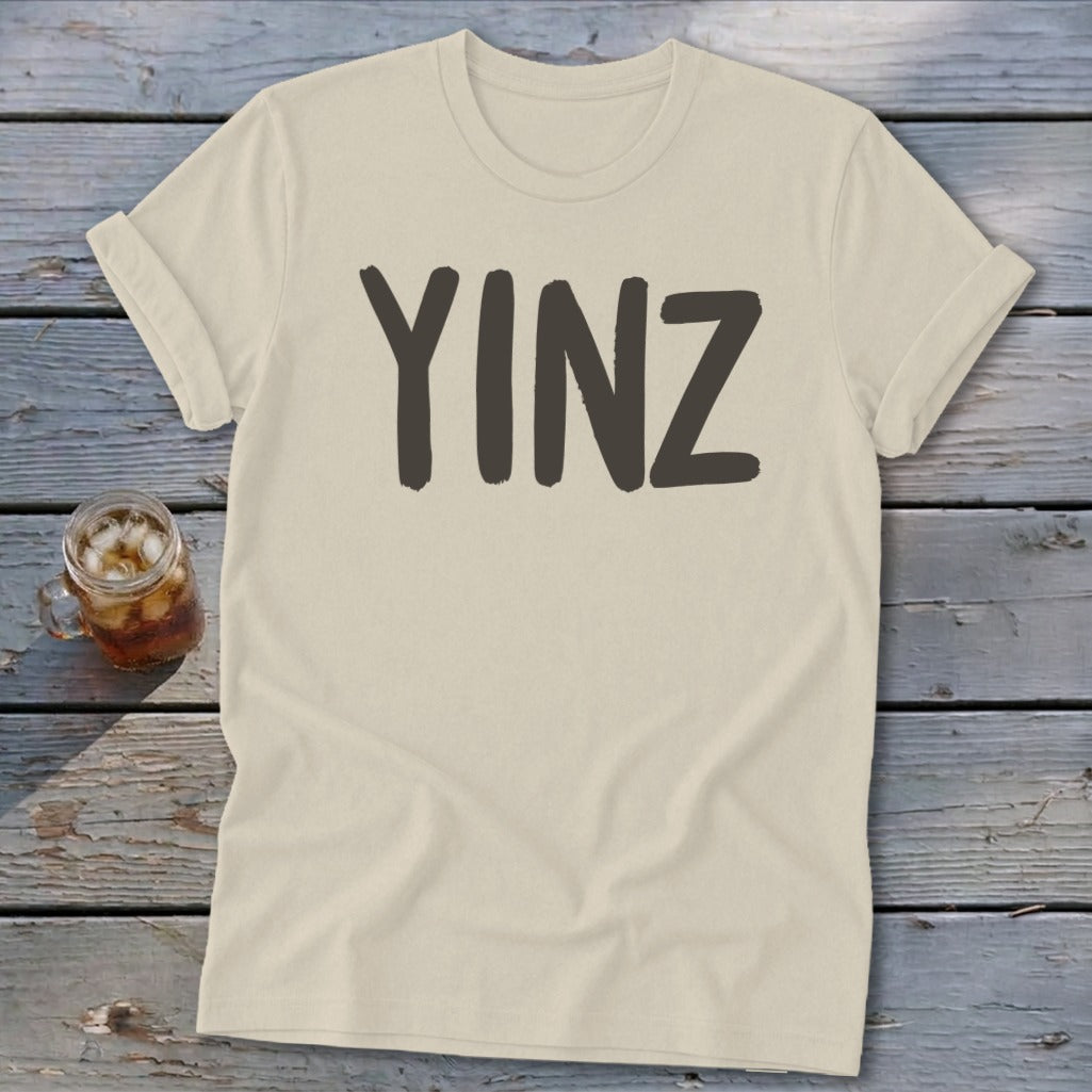 Light beige t-shirt with "YINZ" printed in dark gray on the front.