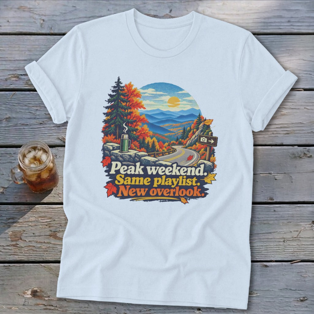 T-shirt graphic with autumn mountain view, road, and text "Peak weekend. Same playlist. New overlook."
