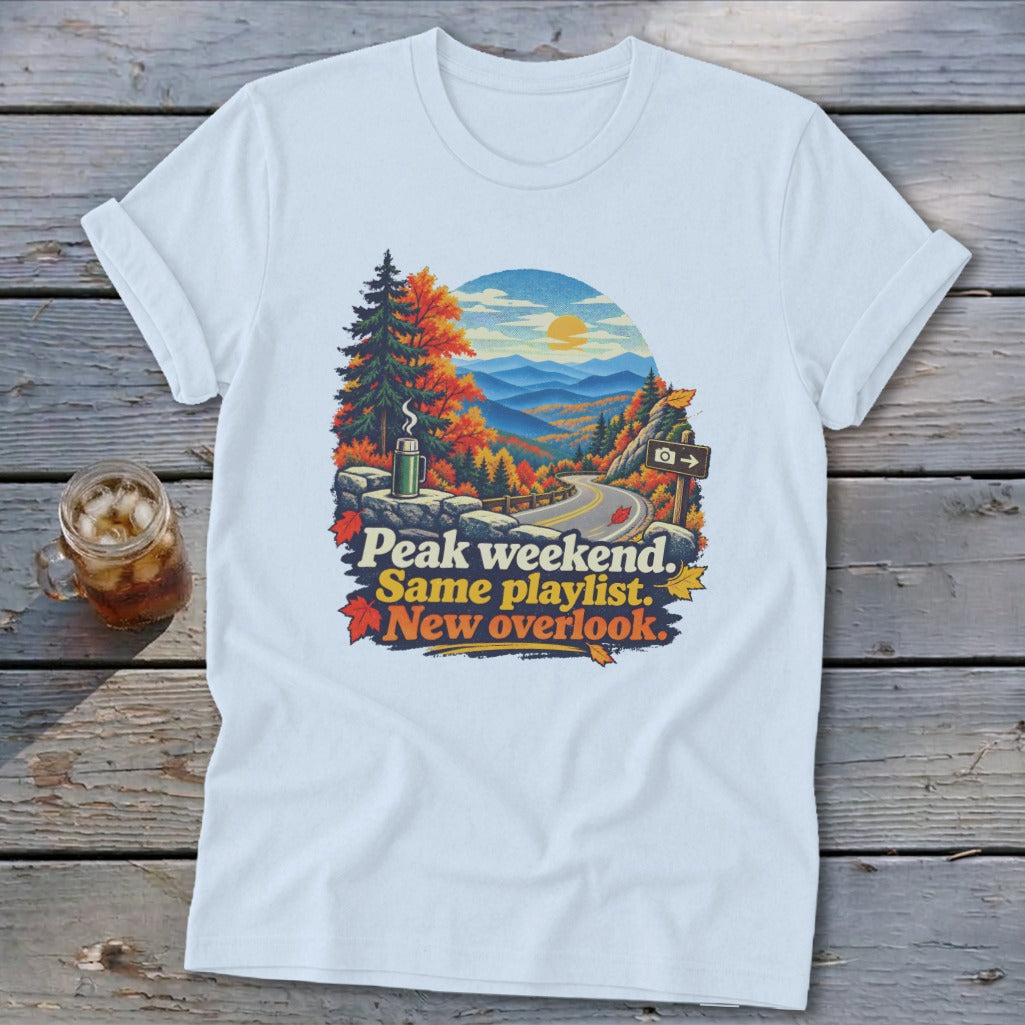 T-shirt graphic with autumn mountain view, road, and text "Peak weekend. Same playlist. New overlook."