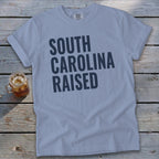 Light blue t-shirt with "SOUTH CAROLINA RAISED" text in dark blue.