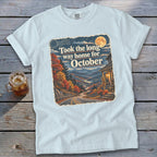 White t-shirt with a graphic of a winding road through autumn mountains and the text "Took the long way home for October."