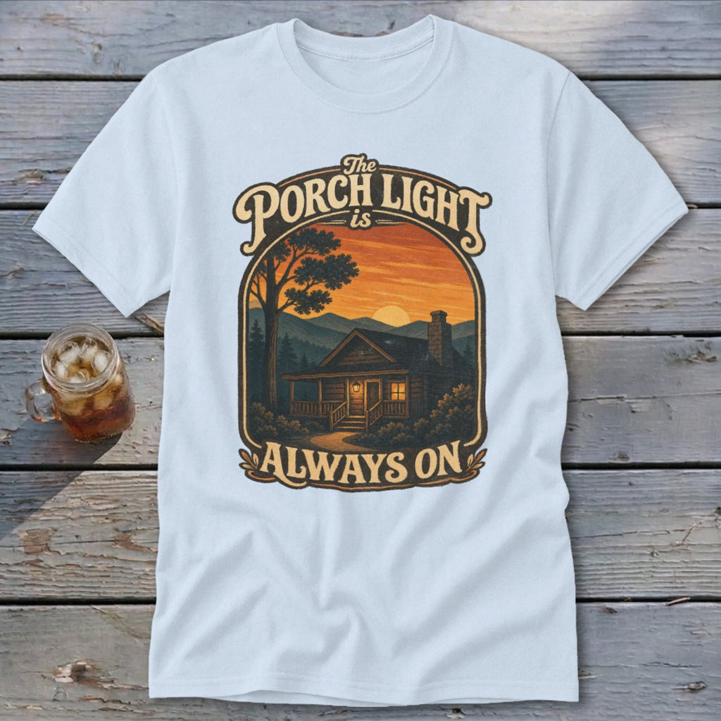 Light blue t-shirt featuring a graphic of a cabin at sunset with text "The Porch Light is Always On".