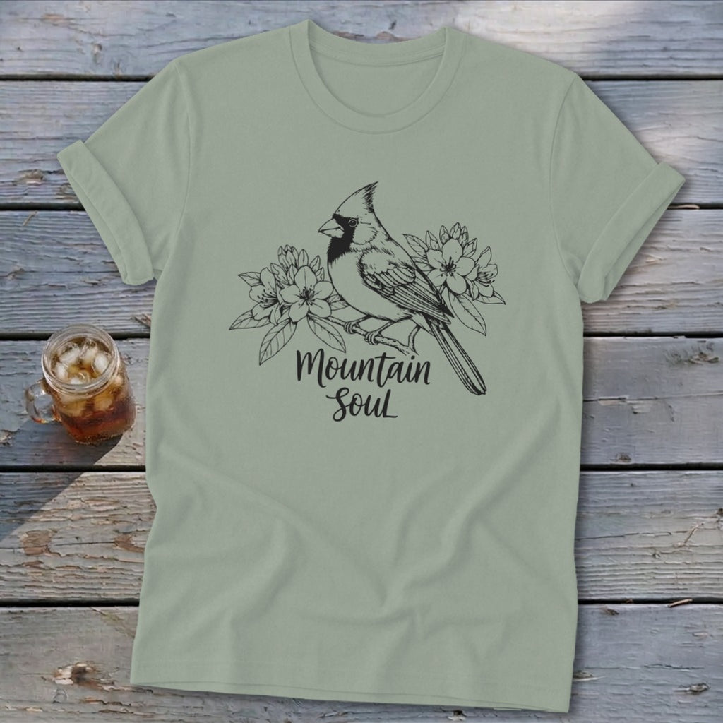 Light green t-shirt with a black line drawing of a cardinal perched on a branch with flowers and the text "Mountain Soul".