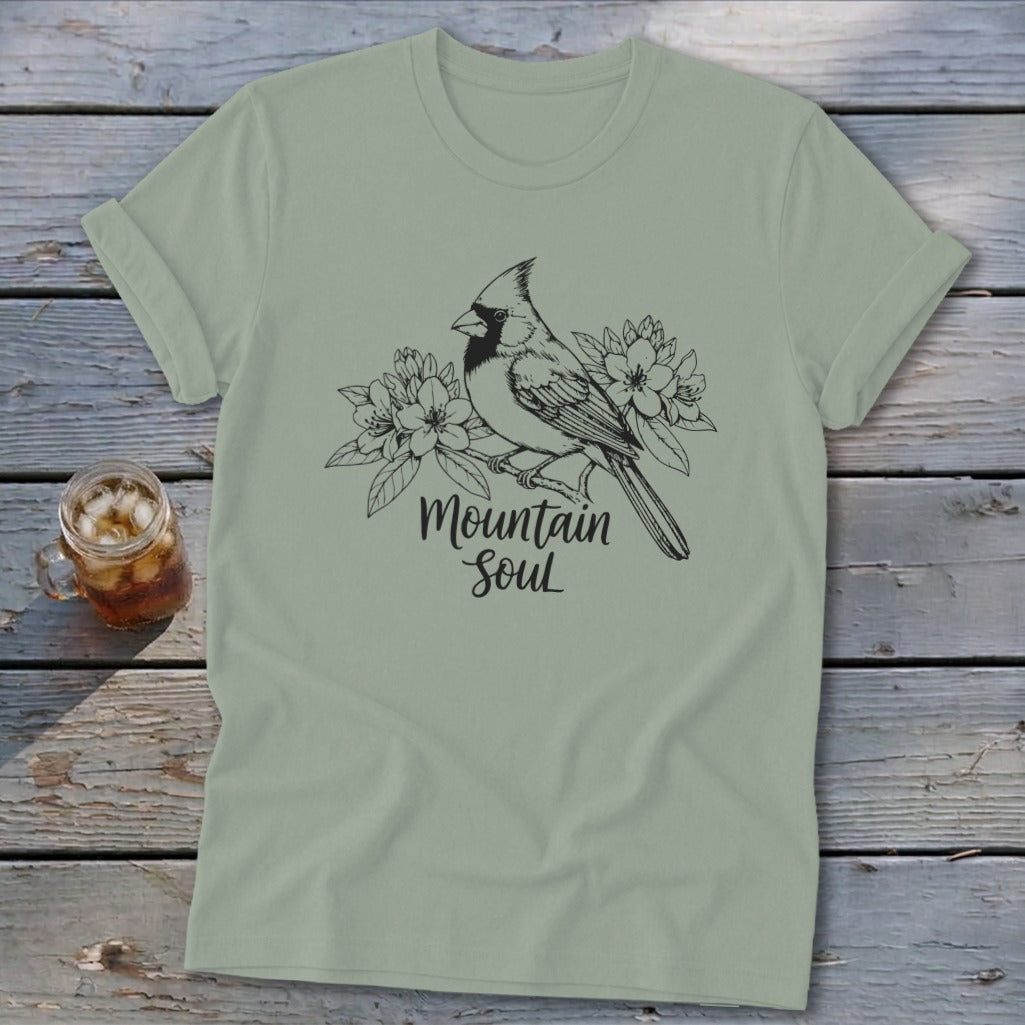 Light green t-shirt with a black line drawing of a cardinal perched on a branch with flowers and the text "Mountain Soul".