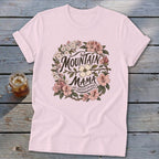 Light pink t-shirt with floral wreath graphic reading "Mountain Mama Raised Em Right."