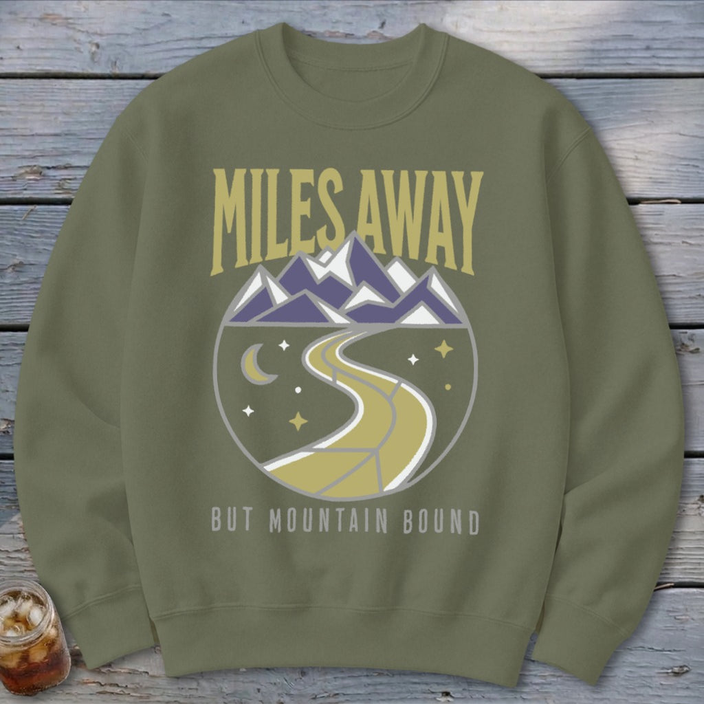 Olive sweatshirt with "Miles Away But Mountain Bound" text and mountain scene graphic.