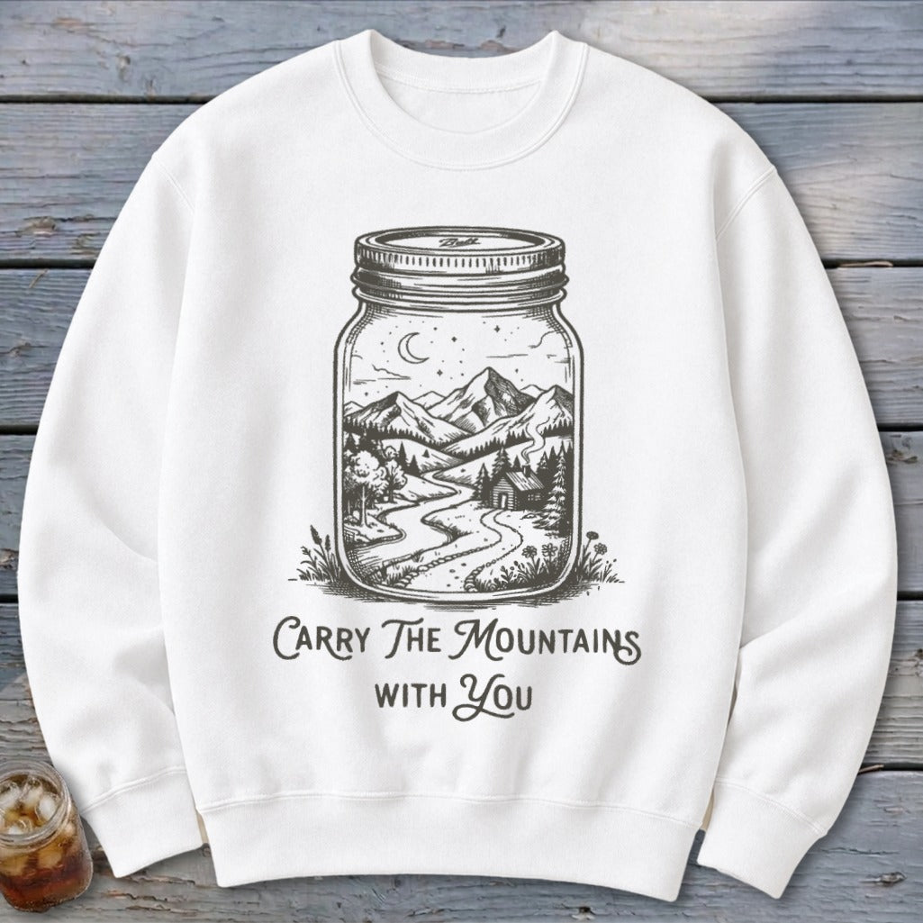 White crewneck sweatshirt featuring a black graphic of a mason jar containing a mountain landscape and the text Carry The Mountains With You.