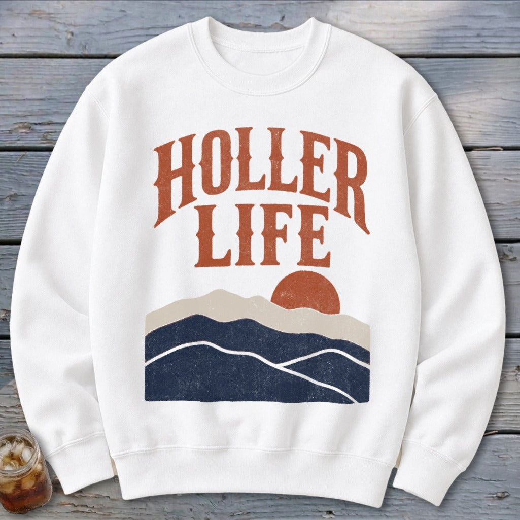 A white crewneck sweatshirt featuring the text HOLLER LIFE above a sunset landscape graphic.