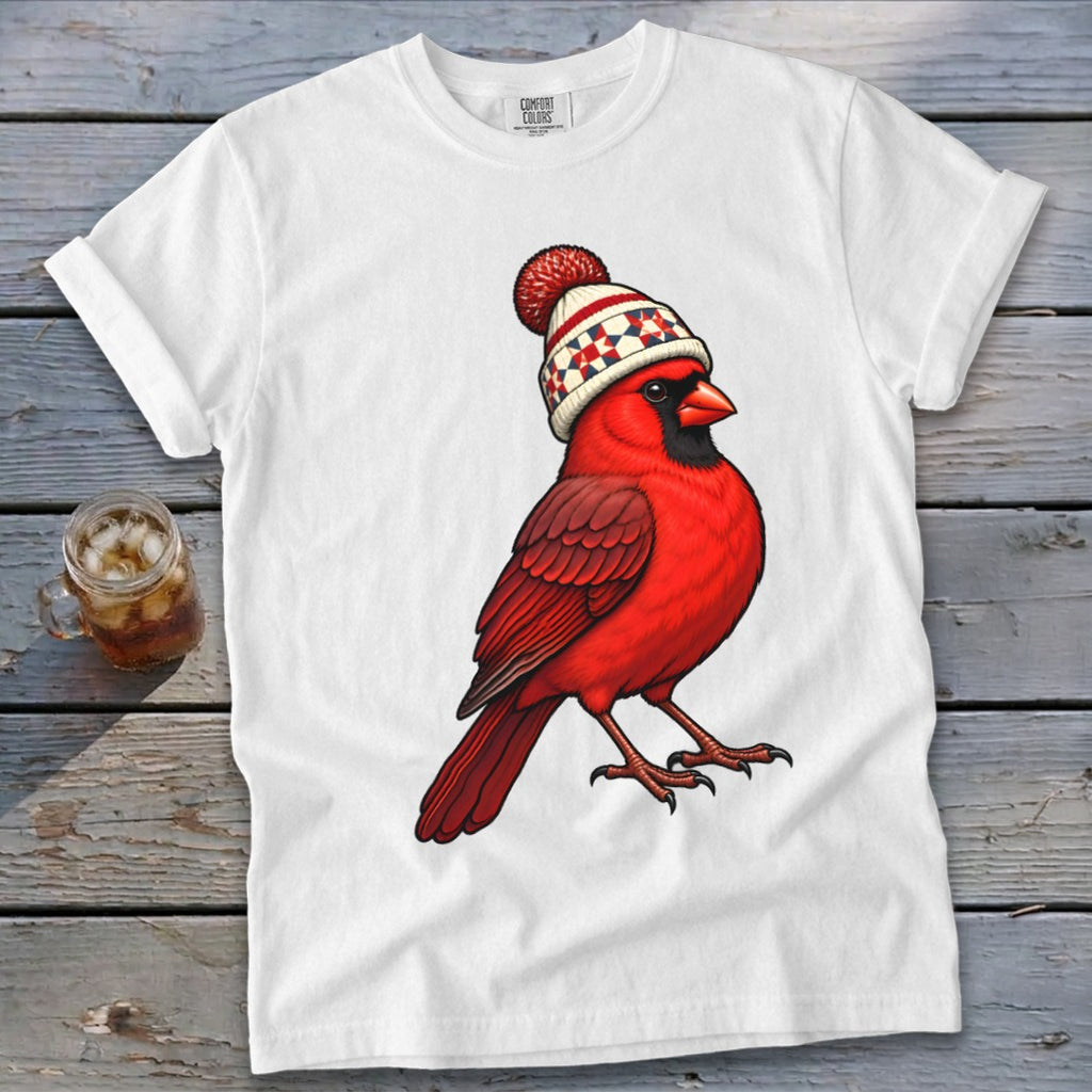 A white short-sleeved t-shirt features an illustration of a red cardinal wearing a patterned winter beanie.