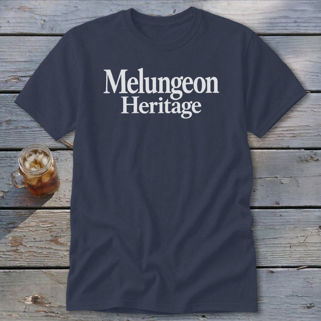 Dark blue crewneck t-shirt featuring the white text Melungeon Heritage, displayed on a wooden surface beside a glass jar of iced tea.