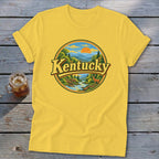 Yellow t-shirt with circular graphic featuring "Kentucky" and a scenic landscape with mountains, river, and deer.