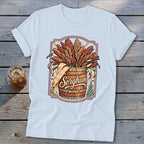 Sorghum stalks overflowing from a wooden barrel, text "Sorghum" on shirt.