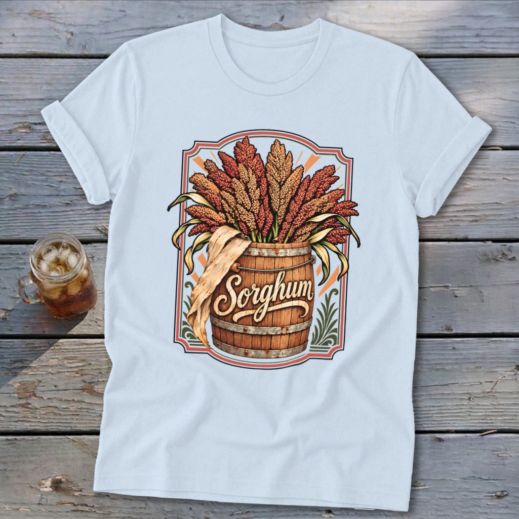 Sorghum stalks overflowing from a wooden barrel, text "Sorghum" on shirt.