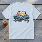 Light blue t-shirt with a heart-shaped mountain sunset design and "Appalachia Strong" text.