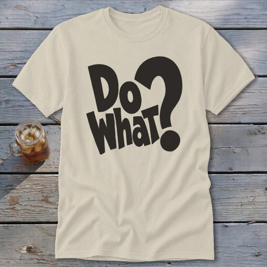 A cream-colored crewneck t-shirt lies flat on a wooden surface, featuring black bold text that reads "Do What?".