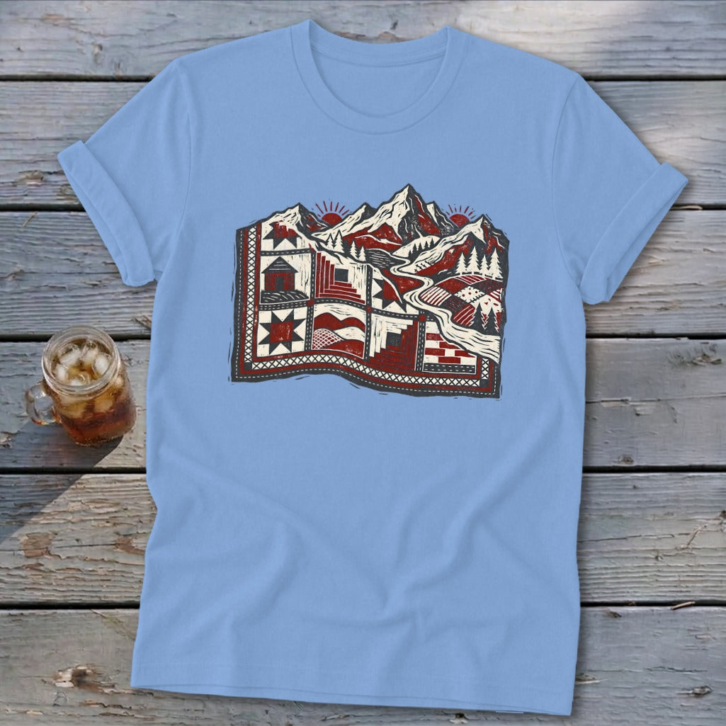 Light blue t-shirt featuring a stylized graphic of a mountain landscape integrated with a patchwork quilt.