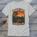 T-shirt with graphic: The porch light is always on, cabin at sunset.