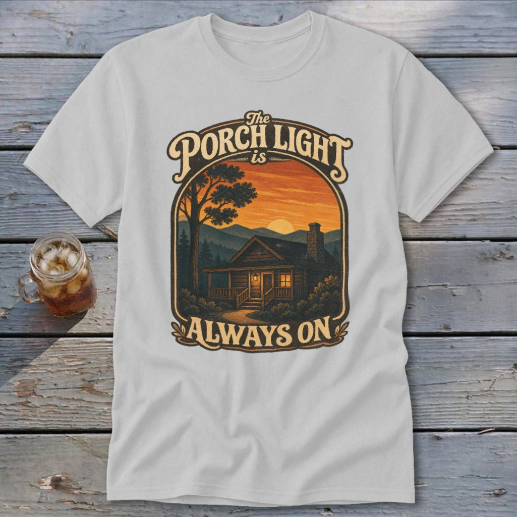 T-shirt with graphic: The porch light is always on, cabin at sunset.
