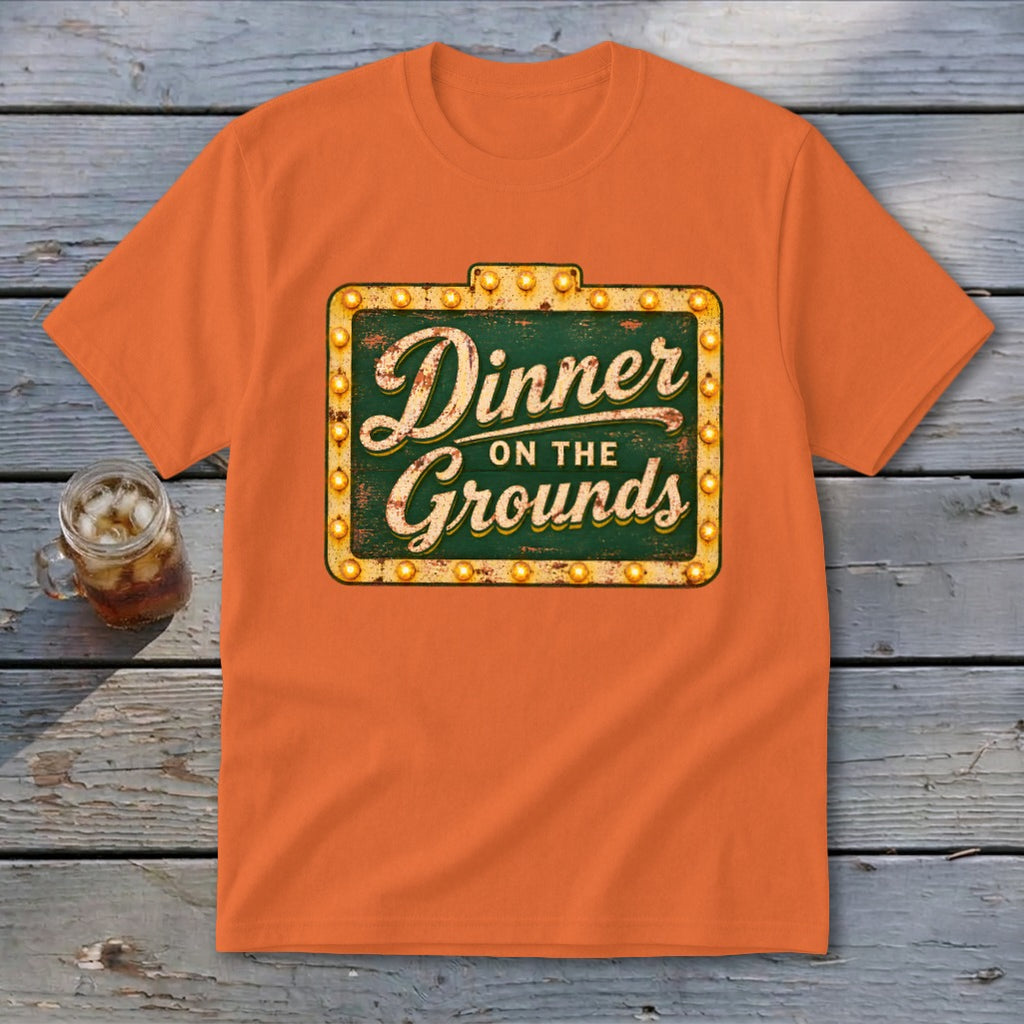 Orange crewneck t-shirt featuring a vintage lighted marquee sign graphic that reads Dinner on the Grounds.