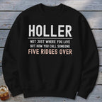 A black crewneck sweatshirt printed with white and peach text that reads, HOLLER NOT JUST WHERE YOU LIVE BUT HOW YOU CALL SOMEONE FIVE RIDGES OVER.