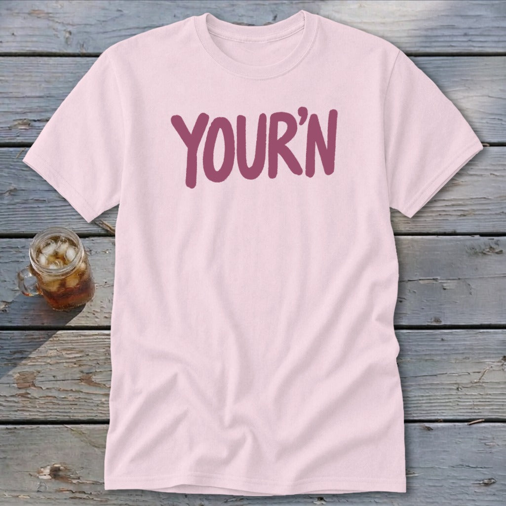 Light pink t-shirt with "YOUR'N" in purple lettering, next to a glass of iced tea.