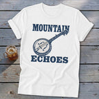 A white t-shirt featuring blue text that reads "MOUNTAIN ECHOES" and a banjo graphic.