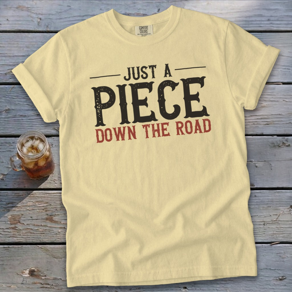 Light yellow t-shirt with "JUST A PIECE DOWN THE ROAD" graphic.