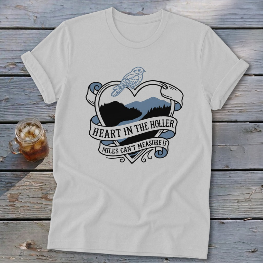 White t-shirt with a heart graphic containing mountains, a bird, and text.