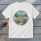 White t-shirt with a circular graphic of North Carolina mountains, river, deer, and sunset.