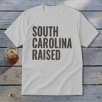 White t-shirt with "SOUTH CAROLINA RAISED" text in dark gray.