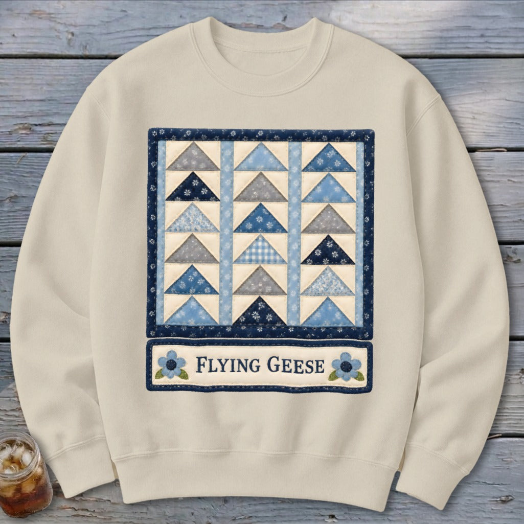 Cream sweatshirt with a blue and grey flying geese quilt pattern and "Flying Geese" text.