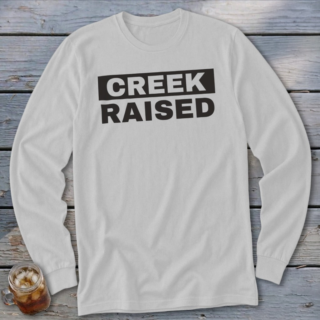 White long-sleeve shirt with black text reading "CREEK RAISED"