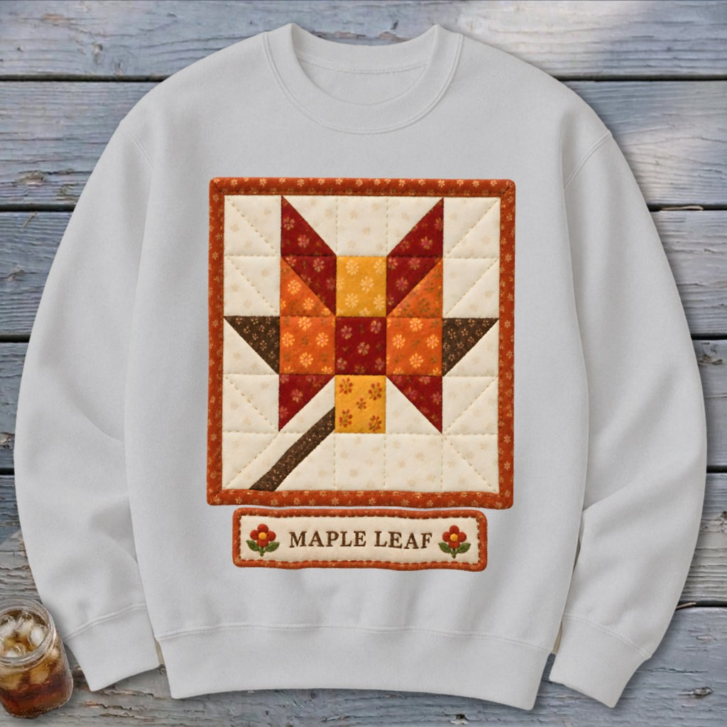 White sweatshirt with a quilted maple leaf design and "MAPLE LEAF" text.